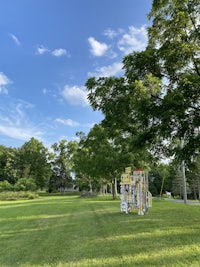 a grassy field with a lot of trees and a blue sky